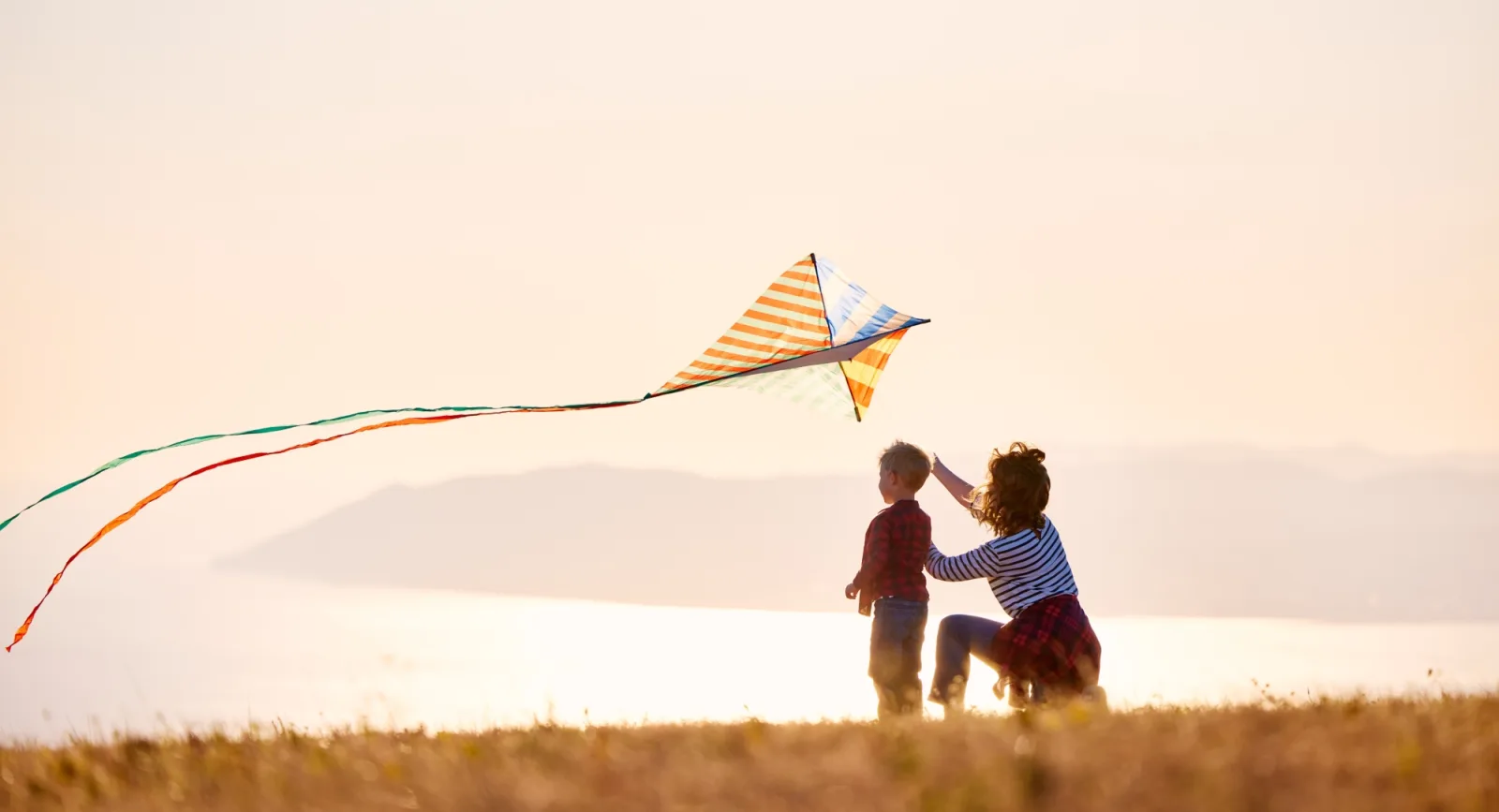 Mother and son in open field flying kite