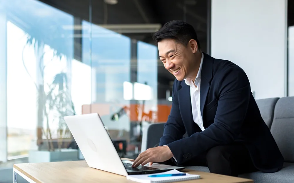 Man smiling and using laptop in office meeting room