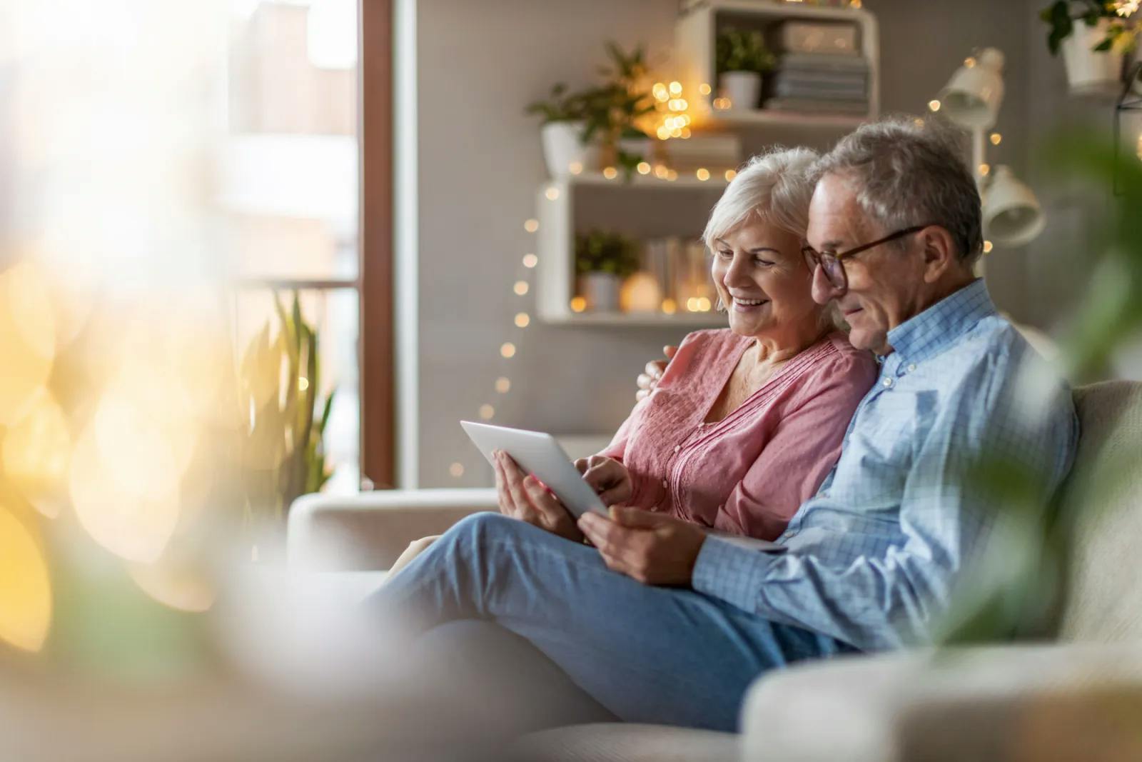 Senior couple sitting on couch looking at tablet