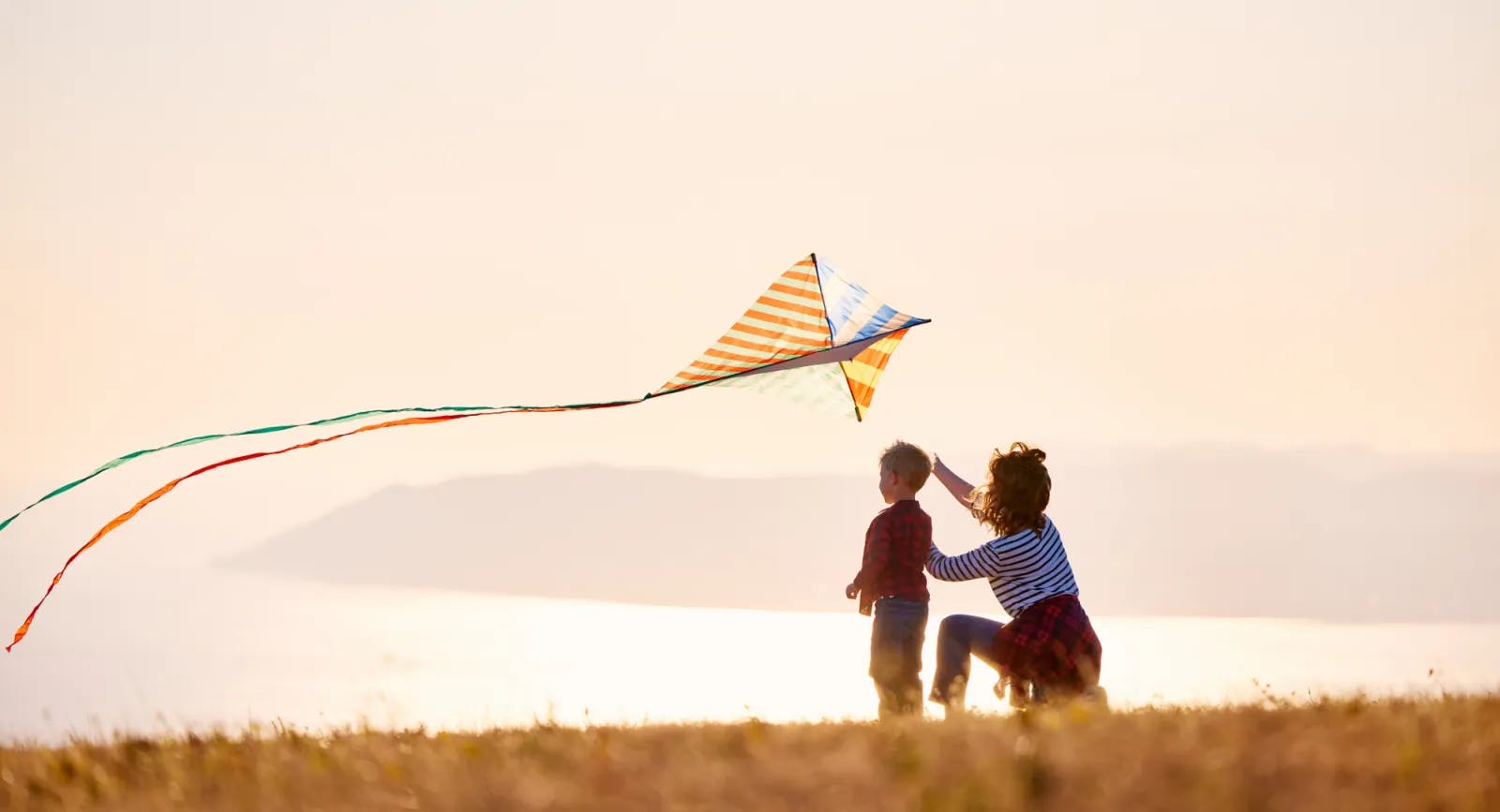 Mother and son in open field flying kite