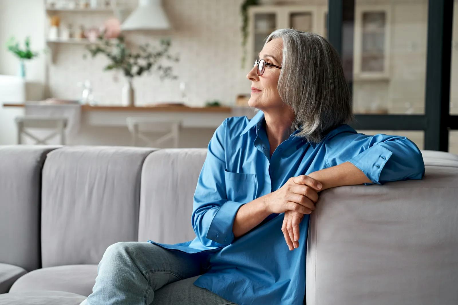 Mature woman sitting on couch looking at window