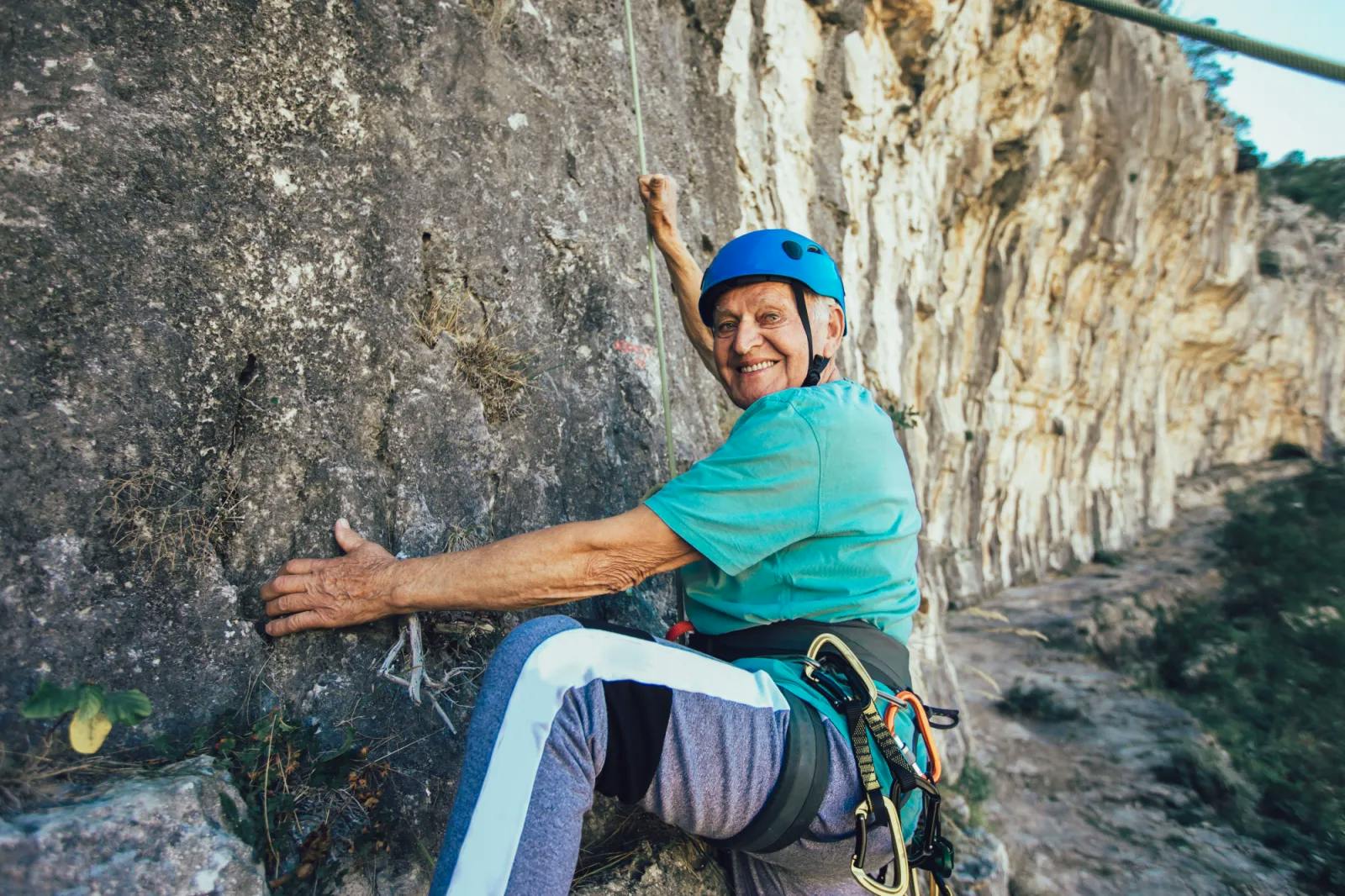 Happy senior man rock climbing