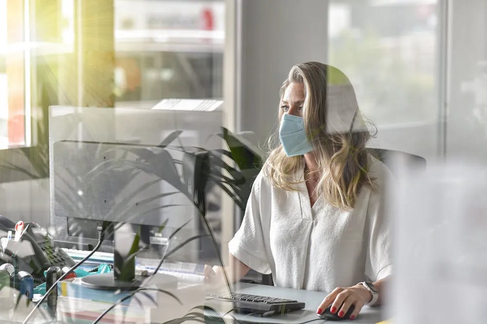 Professional woman wearing mask working on computer in office