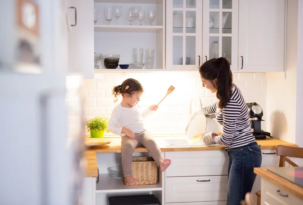 Mother and toddler daughter in kitchen baking
