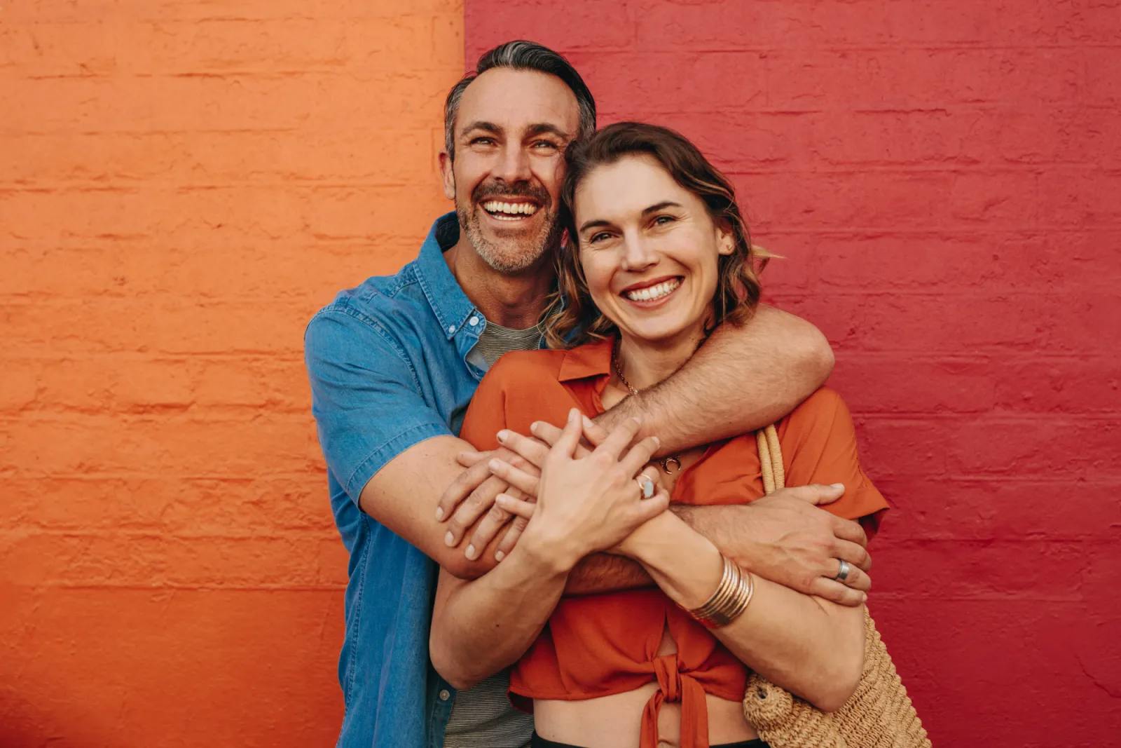 Happy couple embracing against a orange brick background